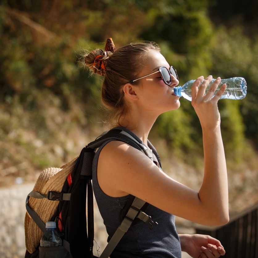 Woman drinking water from a bottle outdoors