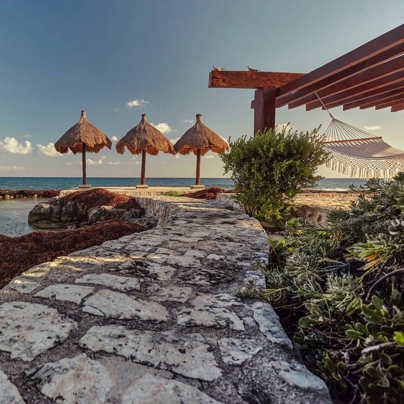 Stone driveway leads to the gazemo with the hammocks facing the sea in Puerto Aventuras in mexico.
