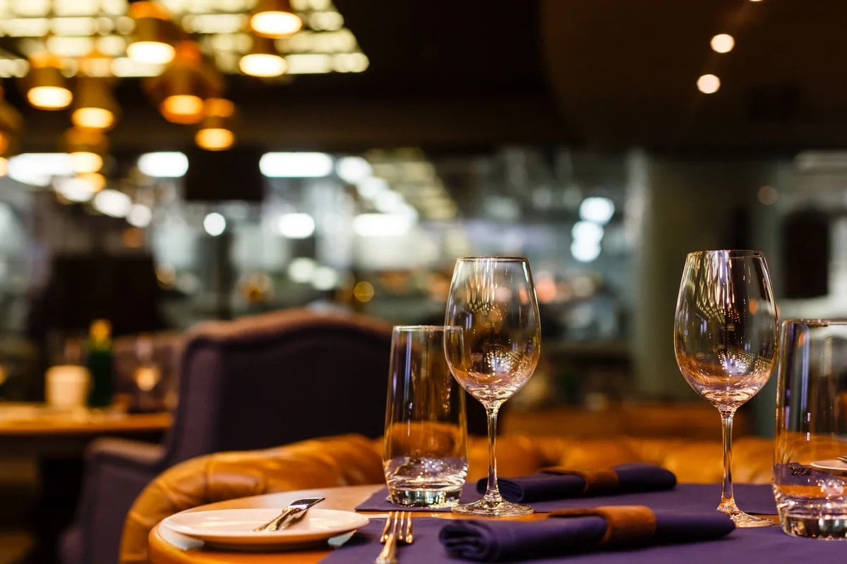 Two empty wine glasses sitting in a restaurant on a warm sunny afternoon.