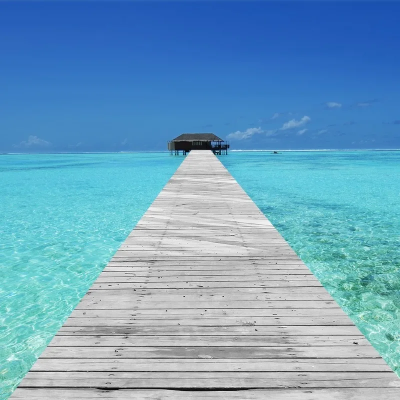 Wooden bridge leading to an overwater bungalow in a tropical lagoon.