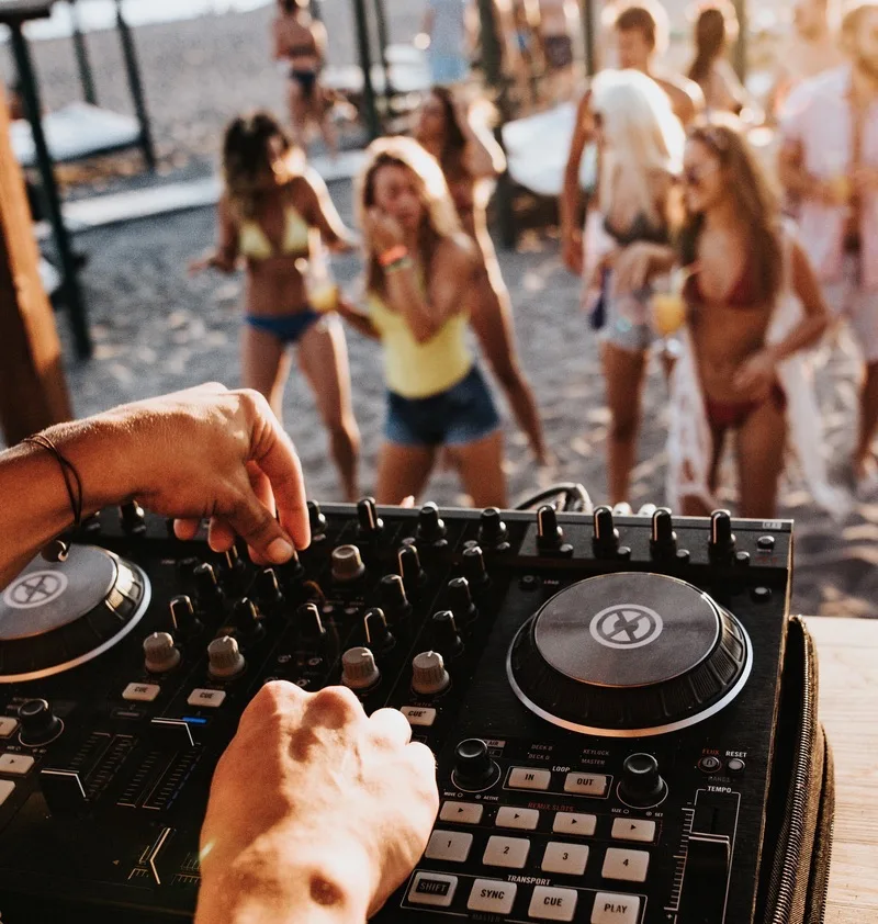 Close up of unrecognizable DJ playing music on turntable during summer beach party.
