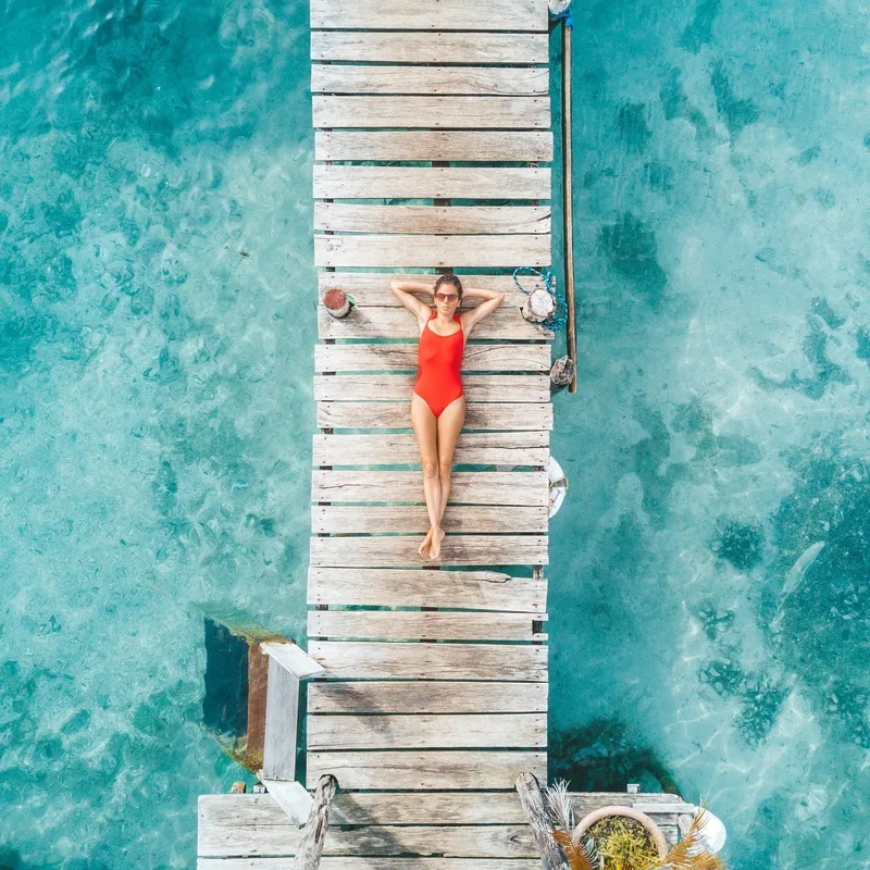 Aerial shot of womann relaxing in a water bungalow