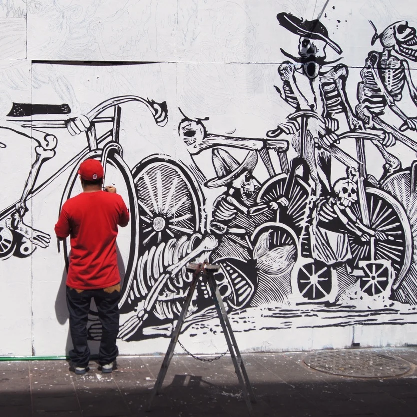 Artist wearing a red shirt and black pants, making street art in Cancun.