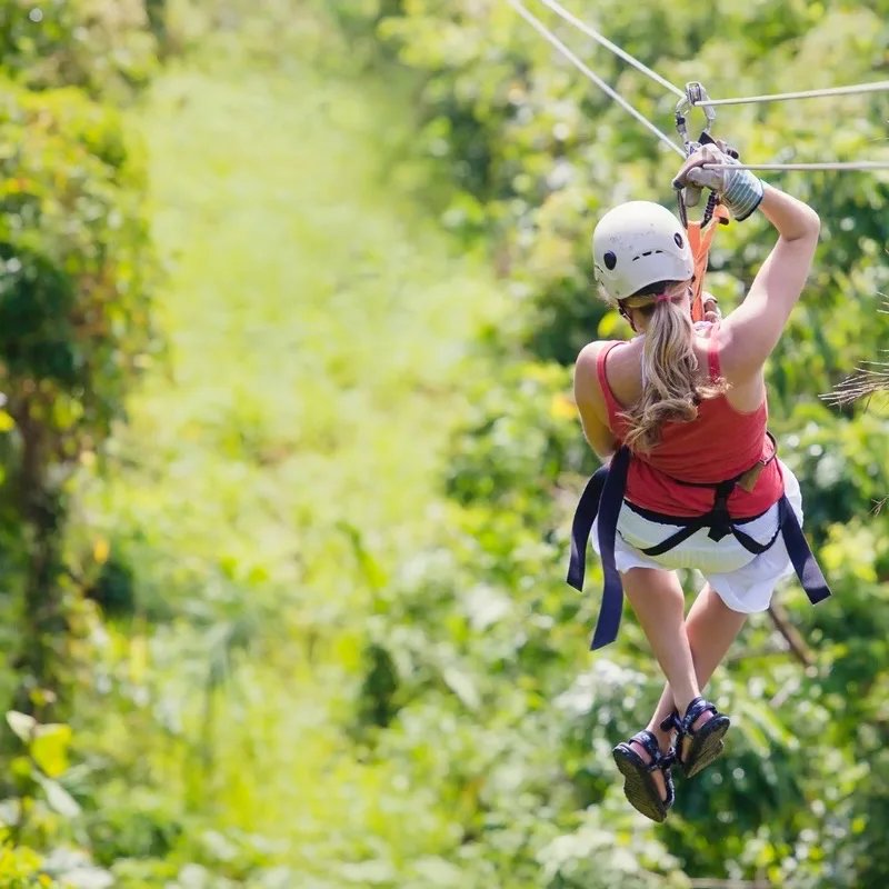 Blonde woman ziplining through the jungle.