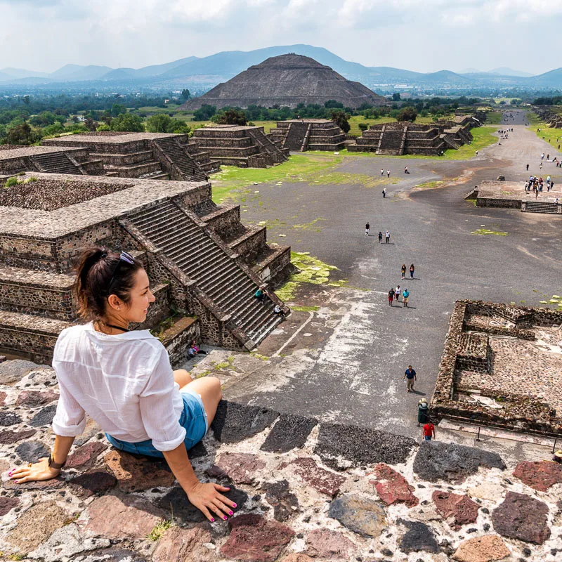 woman sitting on ledge overlooking pyramids