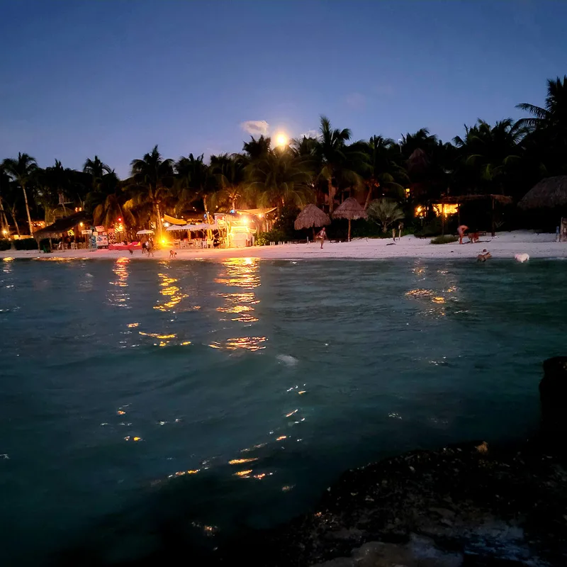 Night time Holbox on the beach with tourists sitting around.