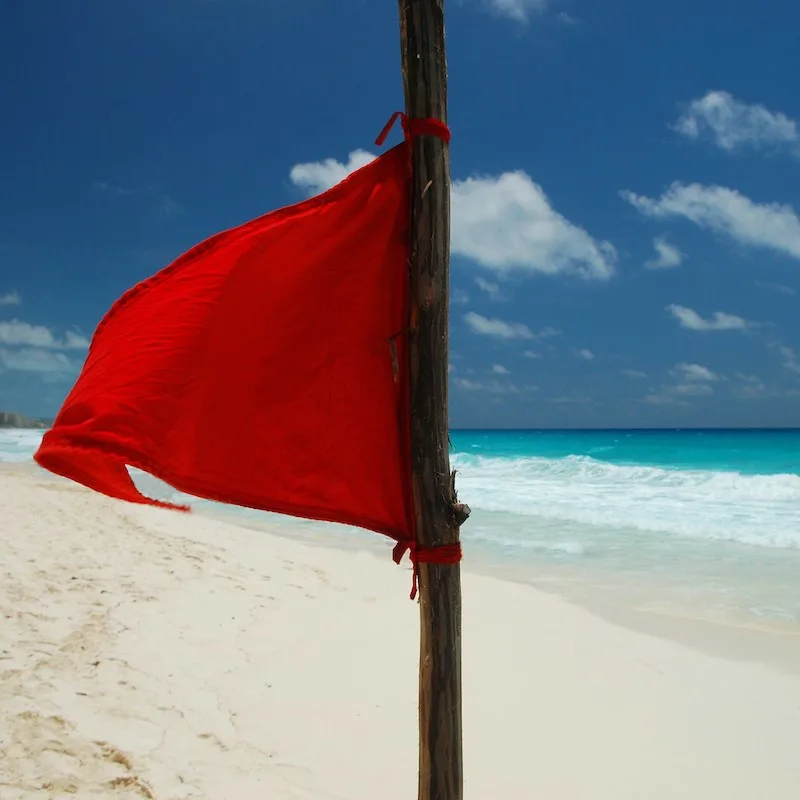 Red flag on a Cancun beach, signaling dangerous waters.