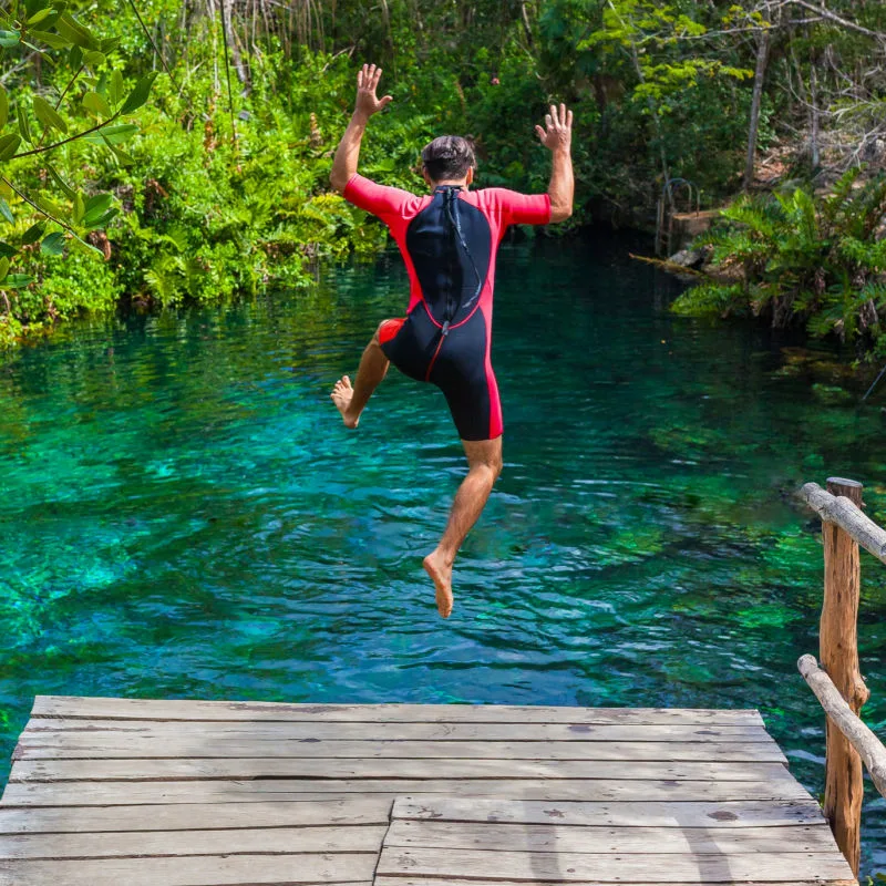 man jumping into cenote