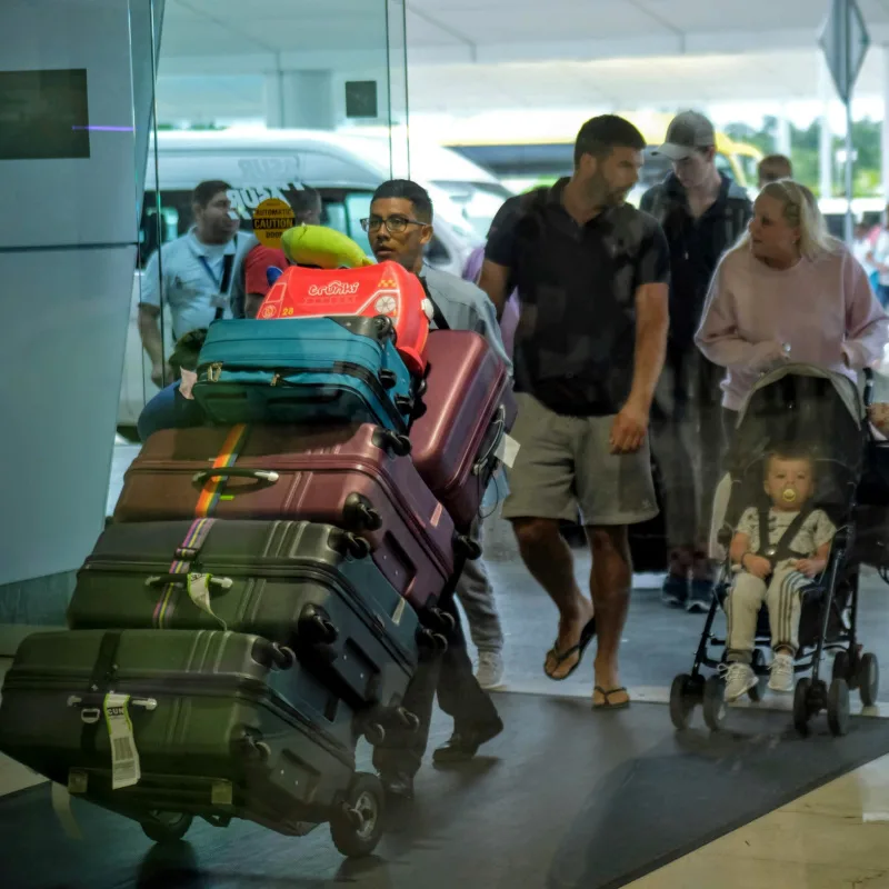 Cancun International Airport passengers with a lot of luggage walking through the airport.