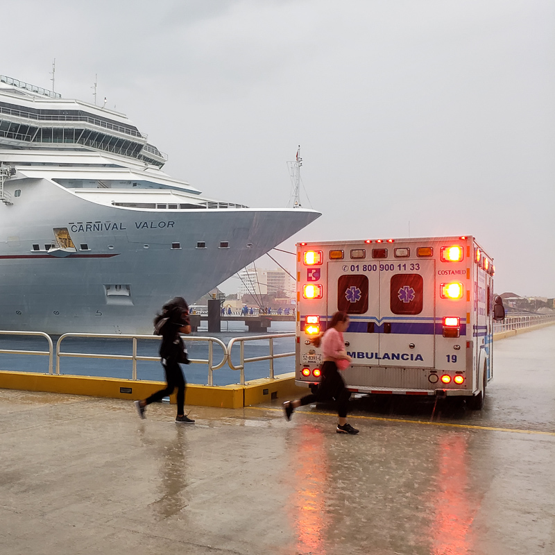 Ambulance by port in the rain attending to an emergency on a cruise ship.