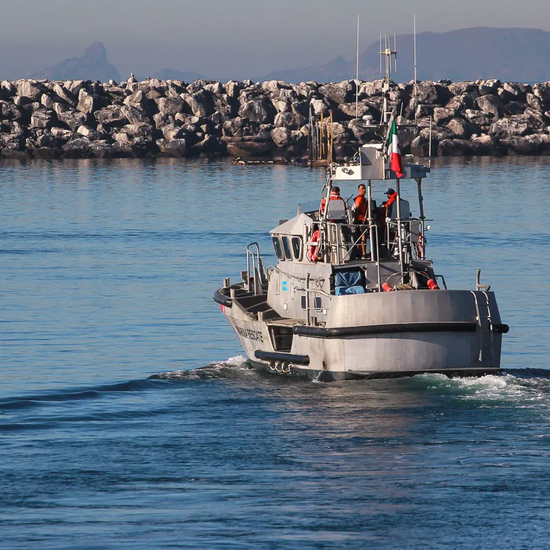 Navy boat in Mexican waters with rocks in the background.