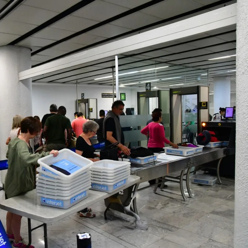 Airport security line at a Mexican airport with totes for people's belongings.