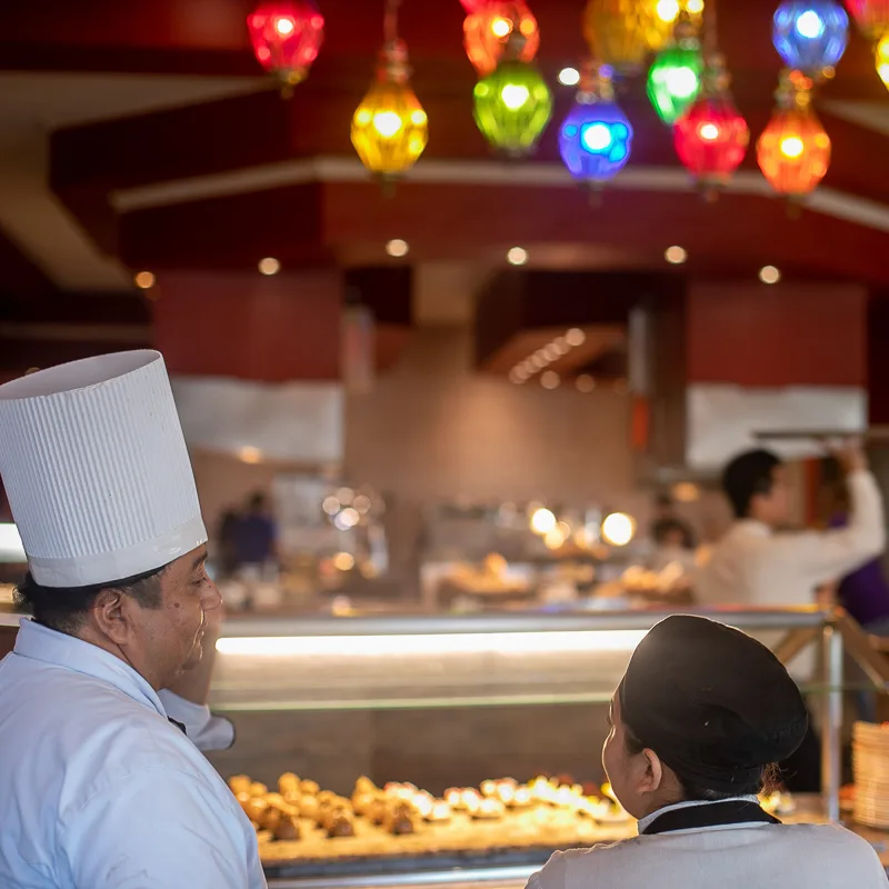 Chef in hotel restaurant speaking to another worker.