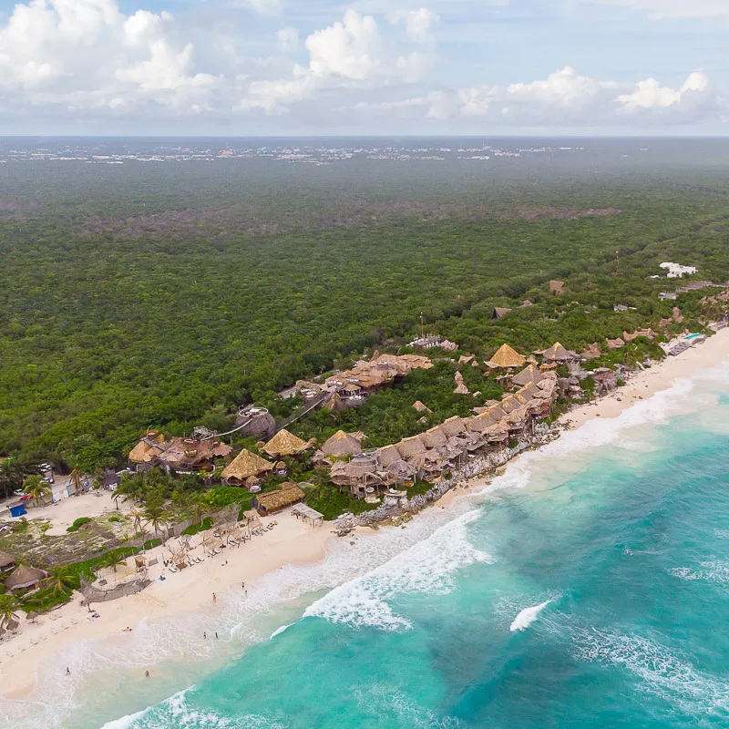 beachline in tulum with resorts and rainforest