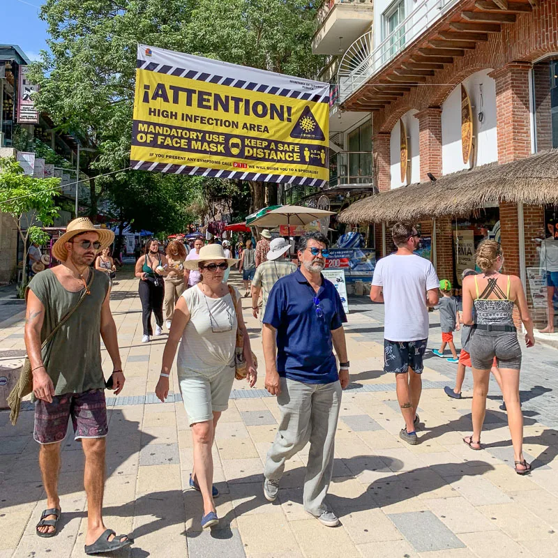 tourists walking under covid sign