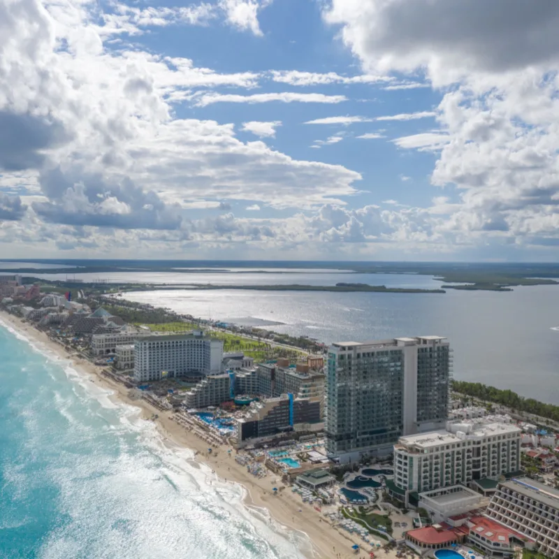 Hotels and resorts in the Cancun Hotel Zone along a beautiful beach with crystal clear blue water.