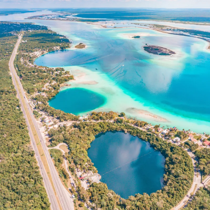 aerial view Cenotes 7 color lagoon deep blue waters in bacalar mexico on a sunny day surrounded by trees 