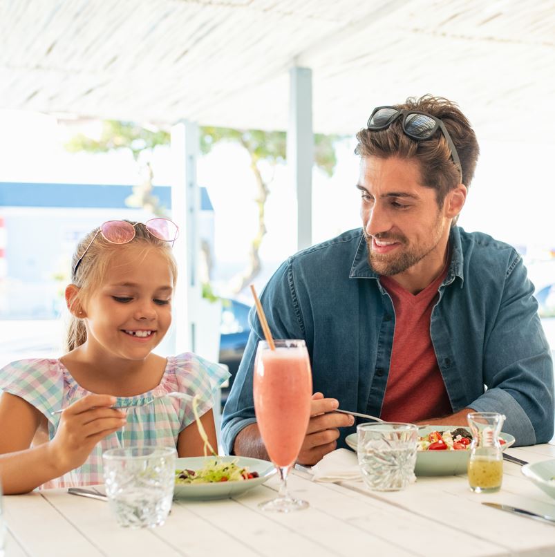 father and daughter eating salad together on vacation