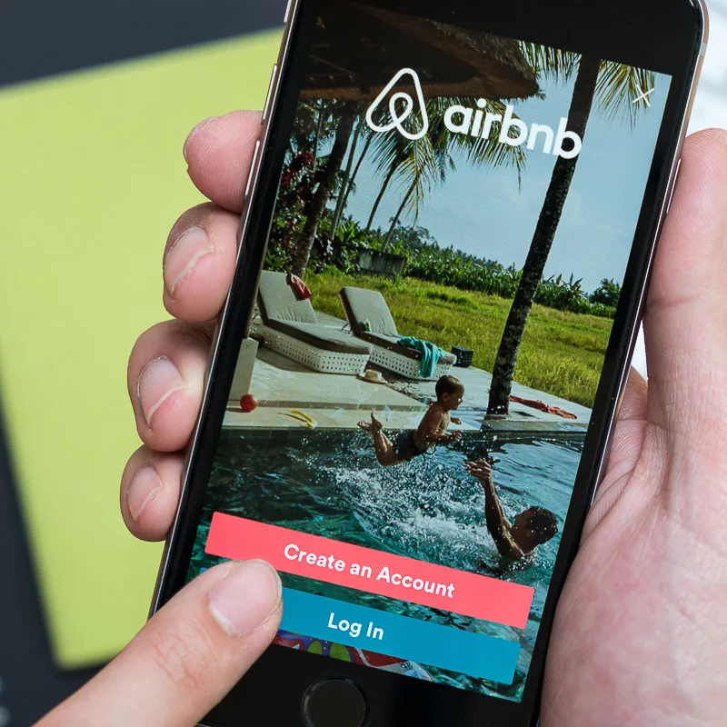 airbnb app homepage with a man holding phone 