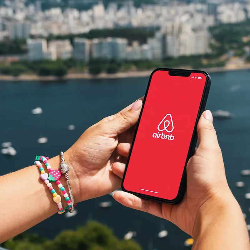 Person using the airbnb app in front of ocean