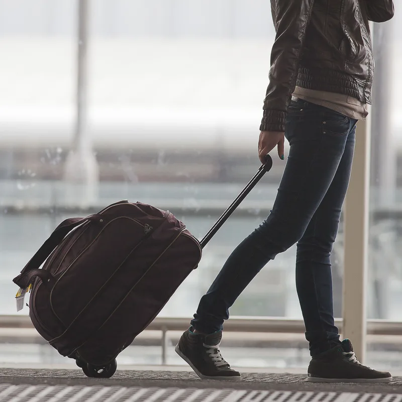 Tourist Walking Through Airport with Carry On Bag