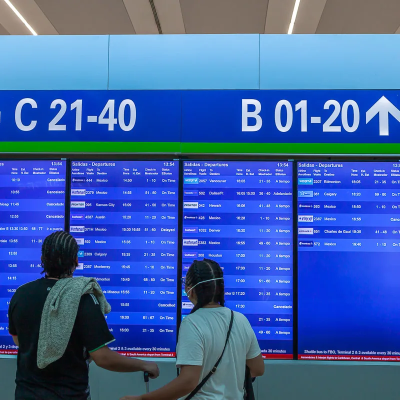 Passengers Reading a Departure Board in Cancun, Mexico