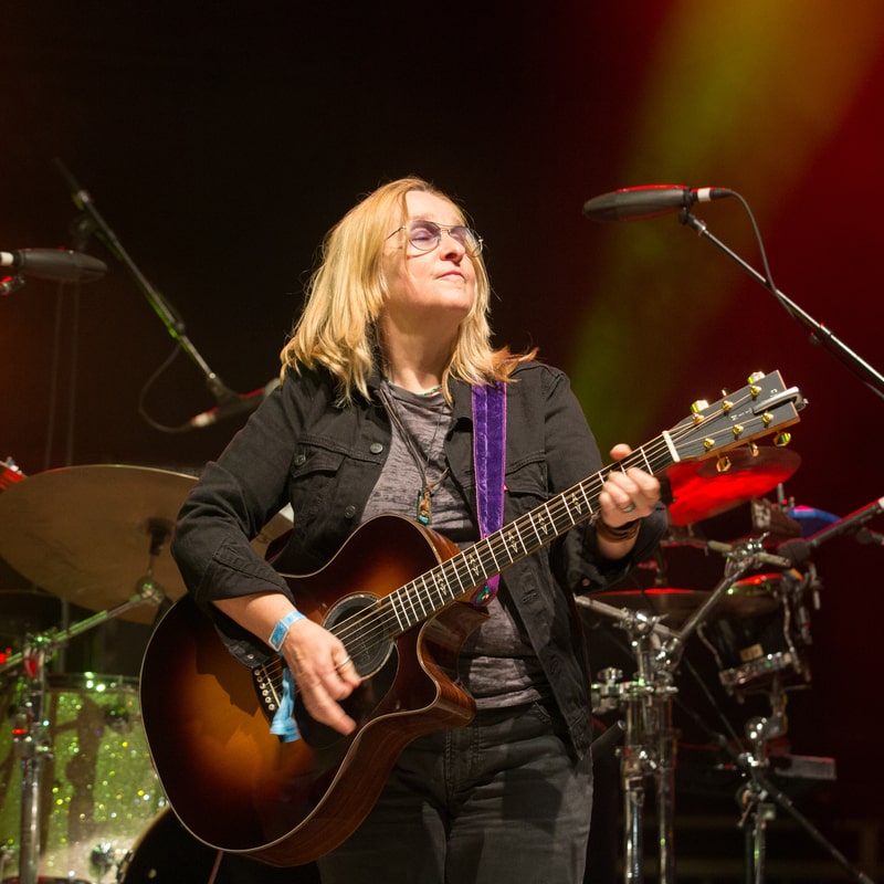 melissa etheridge playing an acoustic guitar at concert