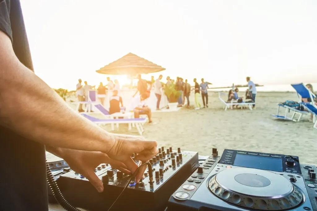 people hanging at the beach with a dj