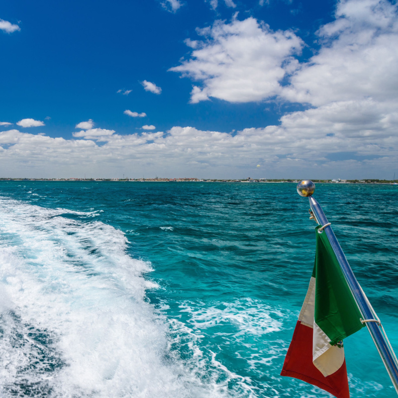 the rear of a ferry at sea with the mexican flag in view