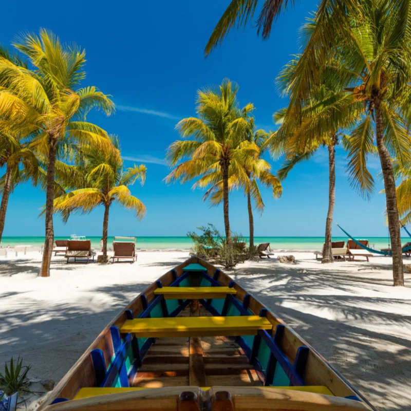 boat along the beach in Holbox, palm trees, beach chairs and sea view.