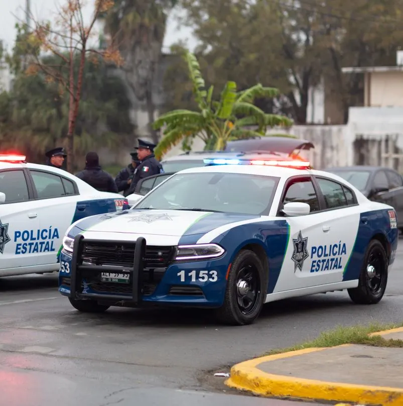 Police Cars in Tulum Mexico parked on the street with policemen standing by the vehicles.