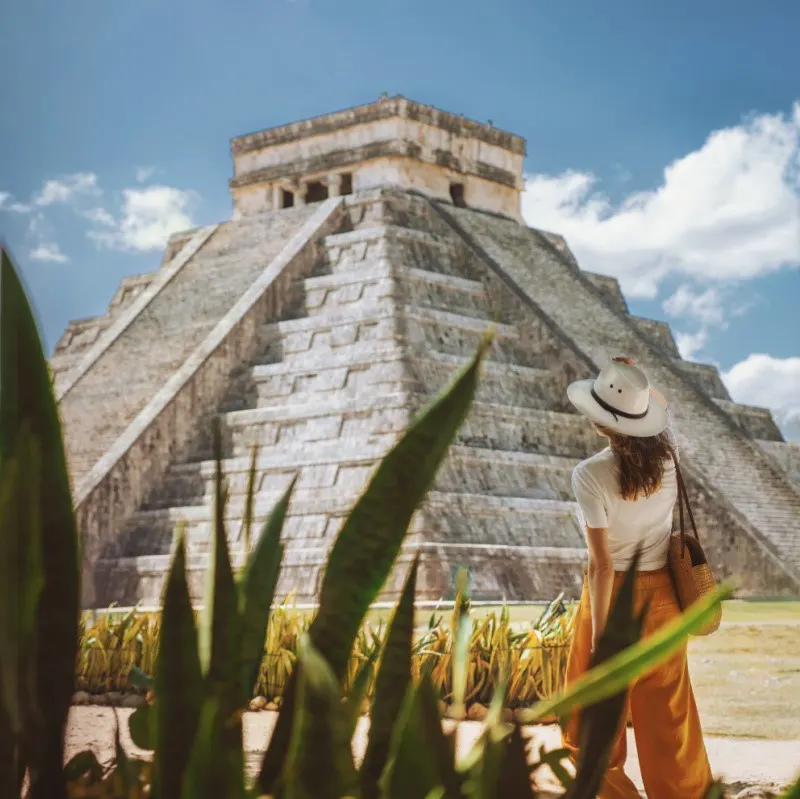 tourist from behind looking out at Chichen Itza, a popular attraction in Yucatan, Mexico.