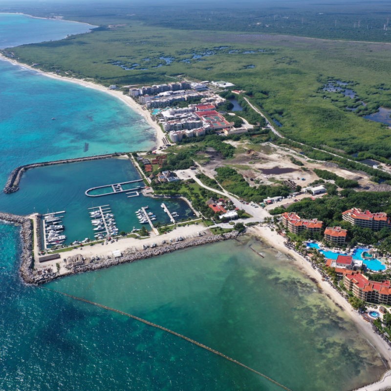 Aerial of Puerto Morelos with a marina and forest in view.
