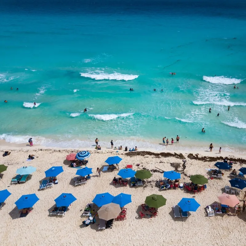 drone image of Cancun Tourists on Beach. beach umbrellas everywhere