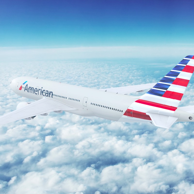 In-flight view of American Airlines Boeing 777 Commercial Passenger Aircraft Flying High Up in the sky above the clouds.