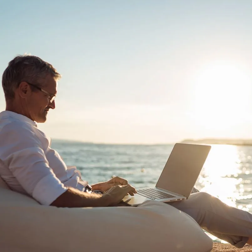 Man working on laptop on beach