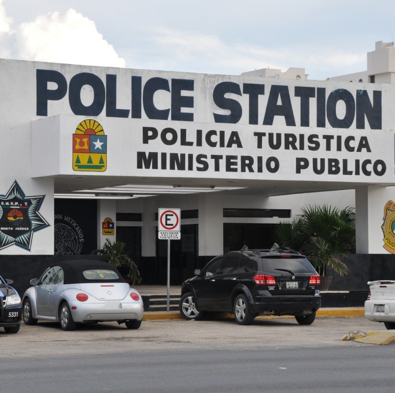 Cancun Police station with vehicles parked in front.