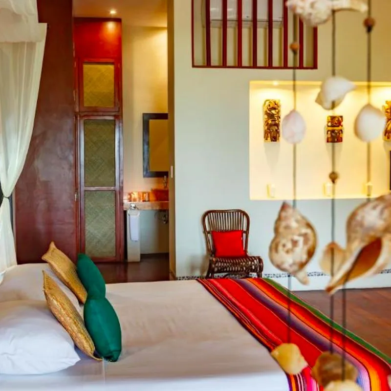 hotel room with colorful pillows and hanging seashells at Villas HM Paraiso del Mar in Holbox, Mexico
