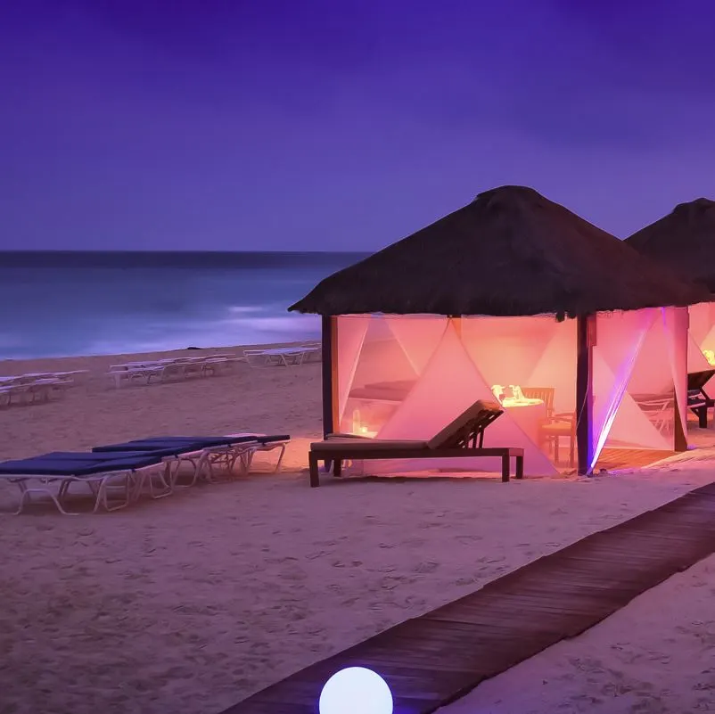 curtain beach huts luxury by the beach in Cancun during the evening.