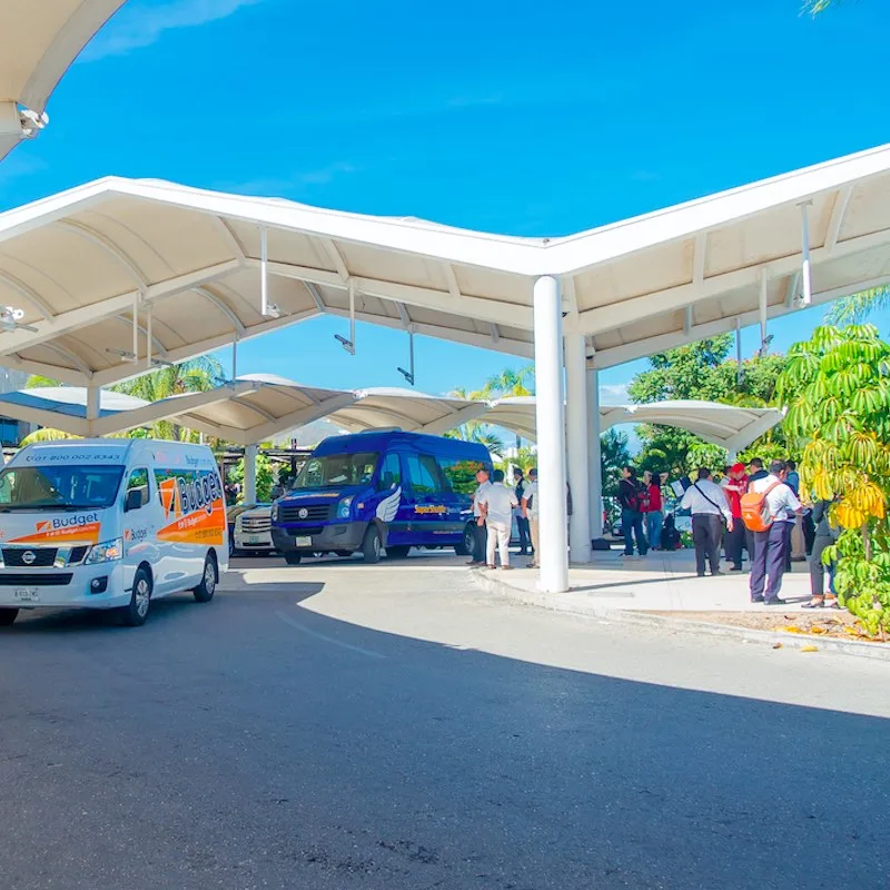 transport vans parked outside of Cancun Airport on a sunny day.