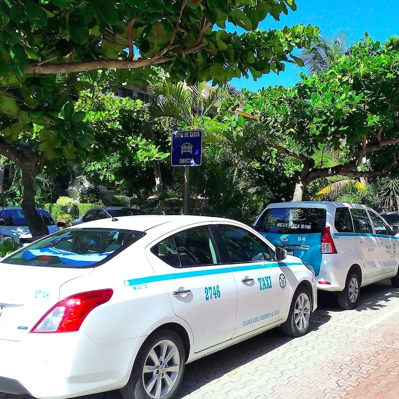 Line of typical white taxi cars parked on street in hotel resort in Playa del Carmen - taxi is popular and cheap means of transport in Riviera Maya, Mexico