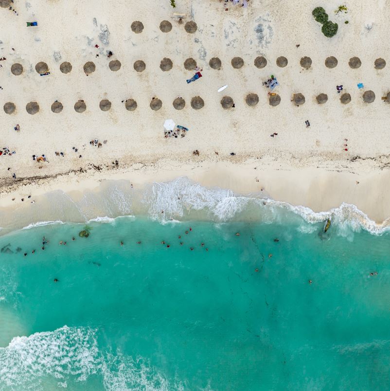 Aerial view of cancun beach half ocean and half sand with tourists swimming and enjoying the beach