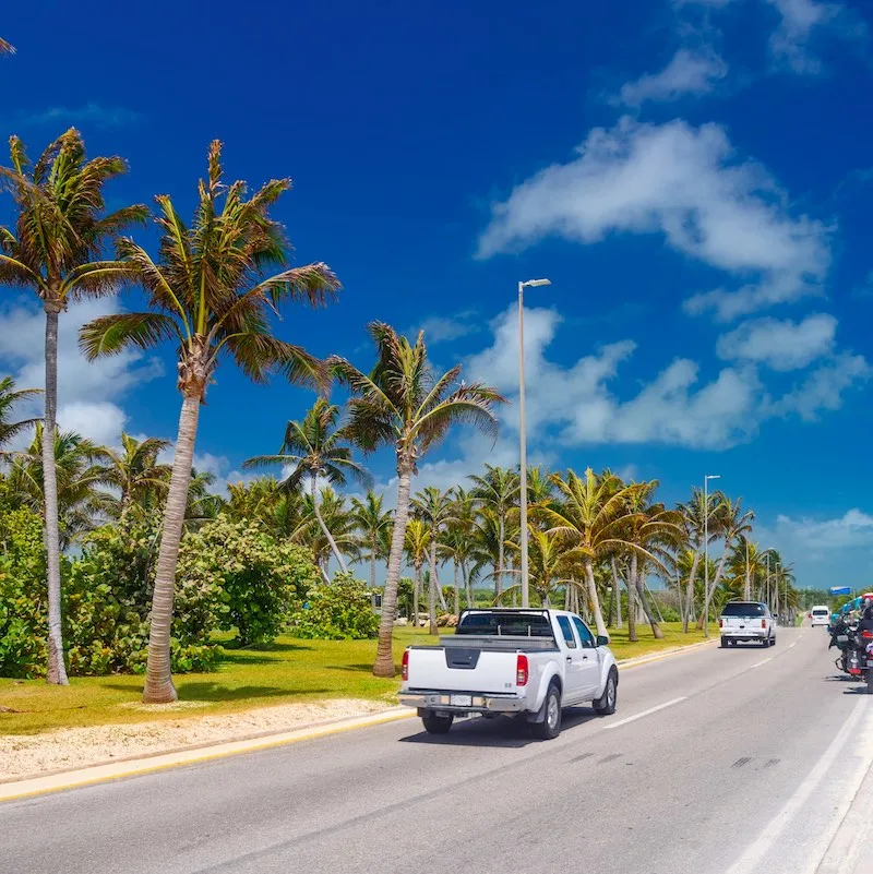 SUV driving on the road with palms on a sunny day near Cancun, Mexico