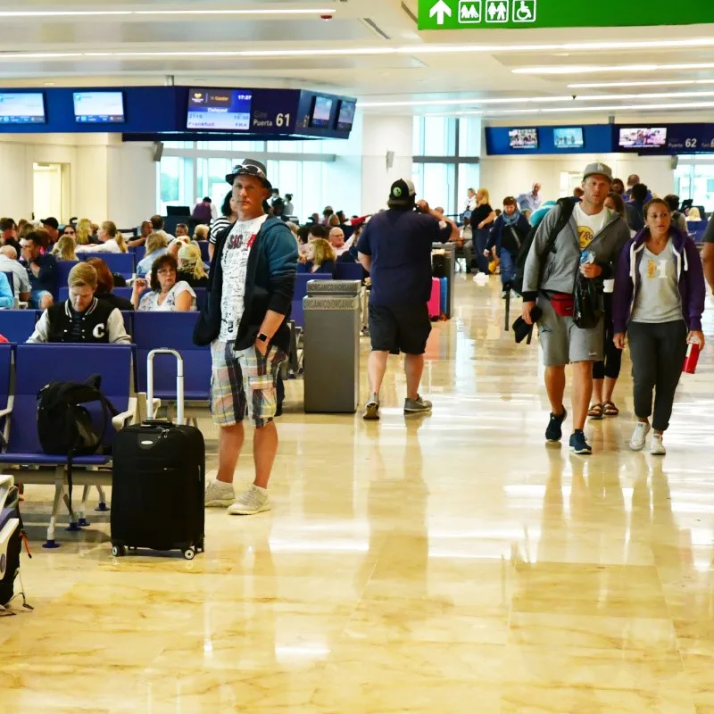 Busy Cancun Airport with people walking around and waiting.