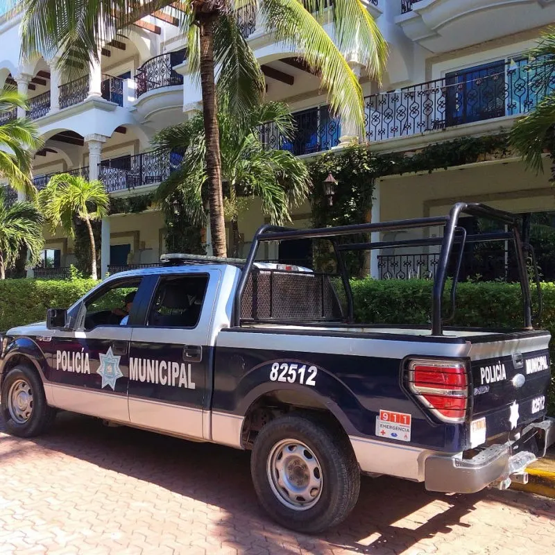 Police vehicle on a tree-lined street in Playa del Carmen.