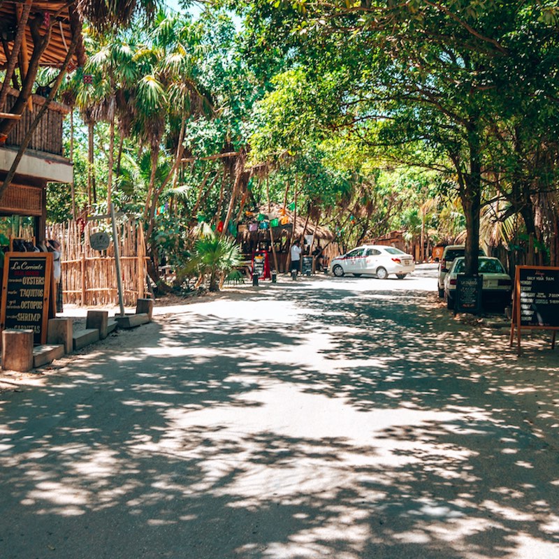 Tulum, Mexico. Shops and restaurants with cars, bicycle parking on both side of the road
