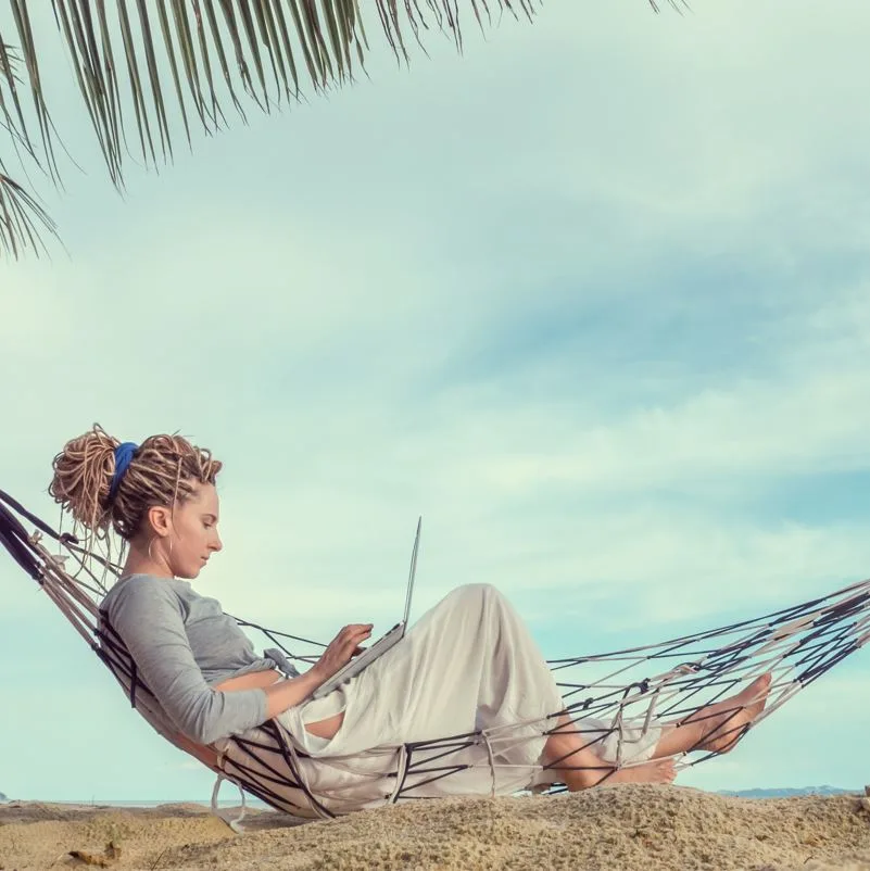 Woman working on laptop on beach
