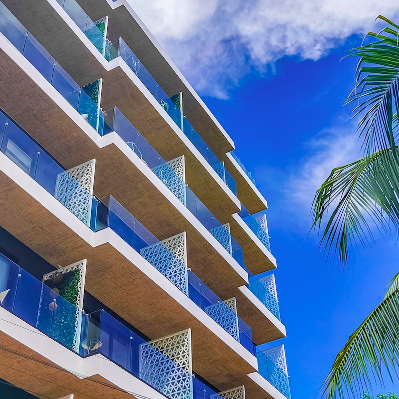 rental property in Playa del Carmen, exterior view of glass windowed patios during the day.