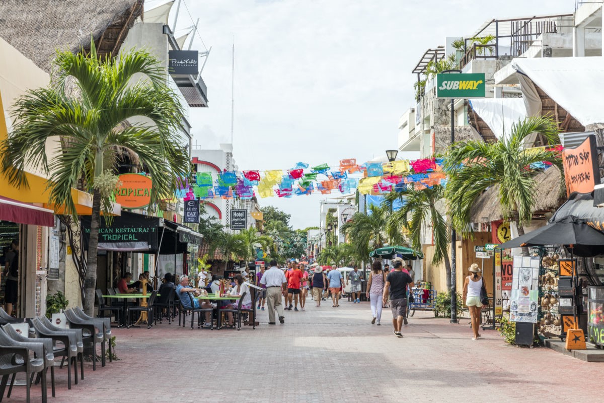 5th Avenue Playa del Carmen, with people walking up and down the street past restaurants and shops.