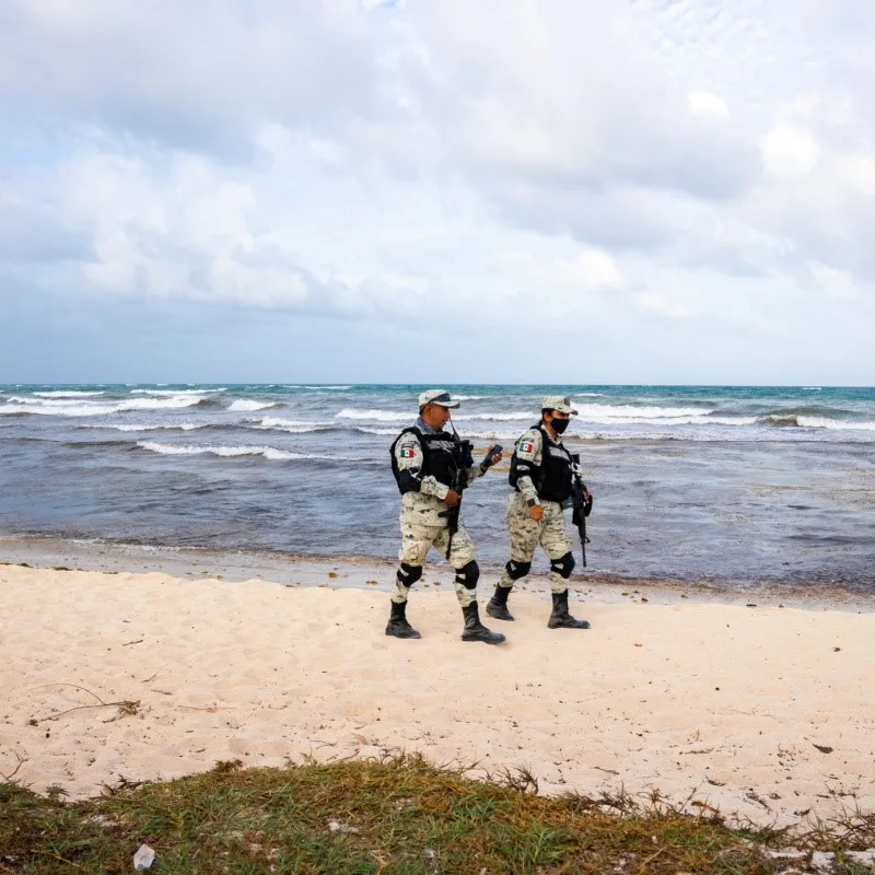 Army Officers on Tulum Beach walking on the sand with the sea in the background.